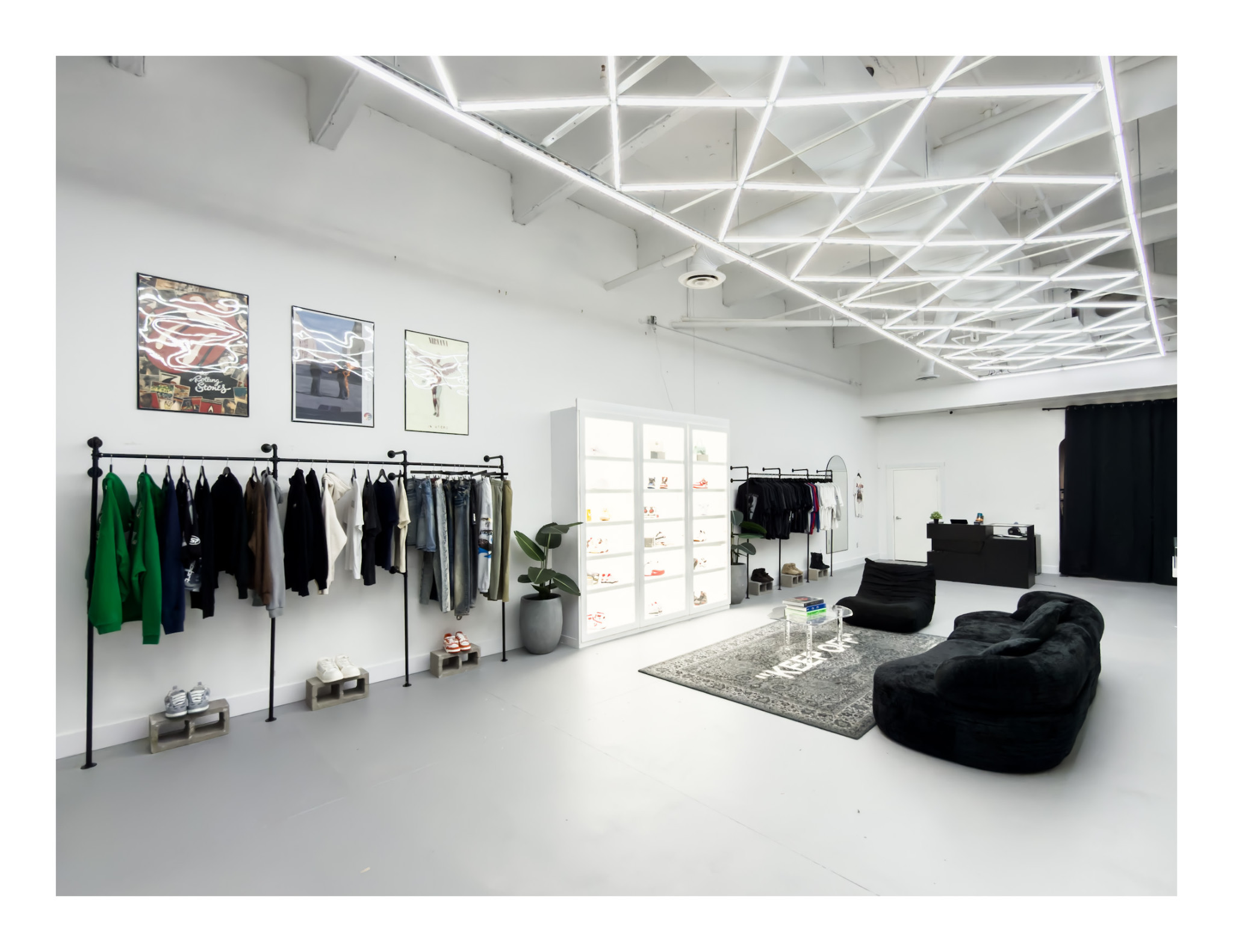 Inside UNCOMMON Dallas, with clothing rails, illuminated display cases and a black lounge seating area